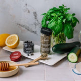 Spices, herbs, and lemons on a kitchen counter with a plant in the background.