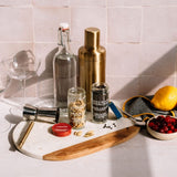 Cocktail-making ingredients and tools on a kitchen counter with a tiled wall background.