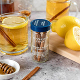 Jar of cinnamon sticks with glasses of iced tea and lemons on a table.