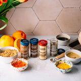 Spices and ingredients on a kitchen counter with a tiled wall background
