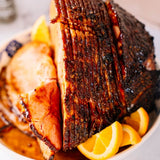 Sliced ham with orange wedges on a plate