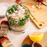 Blender with ingredients on a kitchen counter, including a lemon and spice jar.