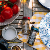 Spices and ingredients on a wooden table with tomatoes and a colander.