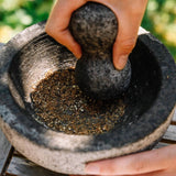 Mortar and pestle with herbs being ground, outdoors