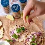 Person seasoning tortillas with spices and lime on a wooden surface