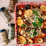 Roasted chicken dish with vegetables on a baking tray, surrounded by spices.