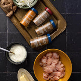 Spices, chicken, and other ingredients on a dark surface