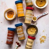Spices including turmeric, paprika, and ground ginger on a light background