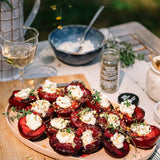 Plated dish of stuffed plums with a glass of white wine on a table.