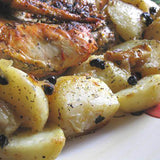 Plated dish of roasted chicken and potatoes with herbs and spices.