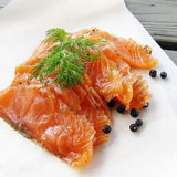 Salmon slices on a white plate with dill and blackberries