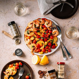 A plate featuring shrimp, fresh tomatoes, and lemon slices arranged on a wooden table.