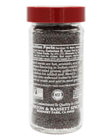 Glass jar with red cap containing black mustard seeds, labeled Morton & Bassett Spices. Nutrition facts and certifications visible.
