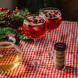 Cranberry rosemary cocktails garnished with fresh rosemary sprigs beside Morton & Bassett Rosemary spice.