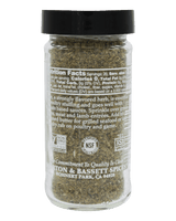 A clear plastic spice jar filled with chopped green herbs, sealed with a black lid, shown against a solid black background. The back of the label is visible, showing text and certification logos including NSF Certified and Non-GMO.