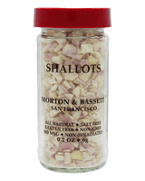 A clear glass jar of Morton & Bassett San Francisco Shallots with a red lid, shown against a solid black background.