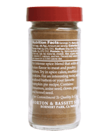 A small clear plastic spice jar with a red lid and a brownish-beige spice blend inside, shown against a solid black background. The front label displays the Nutrition Facts and product details for Morton & Bassett Spice Blend.