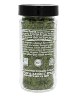 A clear plastic spice jar filled with chopped green herbs, topped with a black lid, shown against a solid black background. The front label displays the brand 'Bassett & Bennett Spices' and product details.