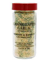 A bottle of Morton & Bassett Granulated Garlic with Parsley seasoning, featuring a red cap and a clear glass container showing the green and beige seasoning blend inside