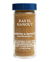A clear glass jar of Ras El Hanout seasoning by Morton & Bassett San Francisco, filled with brown spice blend and topped with a dark blue lid