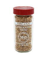 Glass jar of organic coriander seeds with a red lid, labeled "M&B Spices." The jar highlights "all natural" and "salt free." Black background.